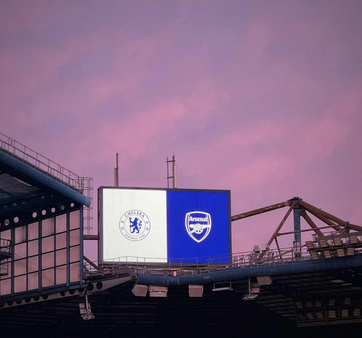 The big screen at Stamford Bridge lit up against a pink evening sky before kick-off.