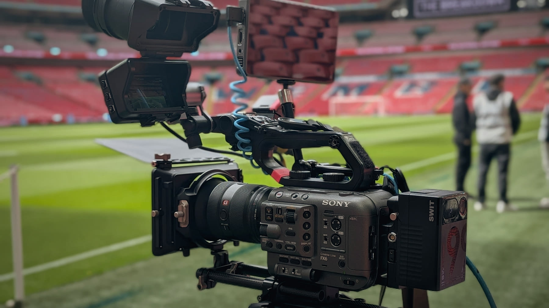 A broadcast camera rigged pitchside at Wembley, with our crew behind it.