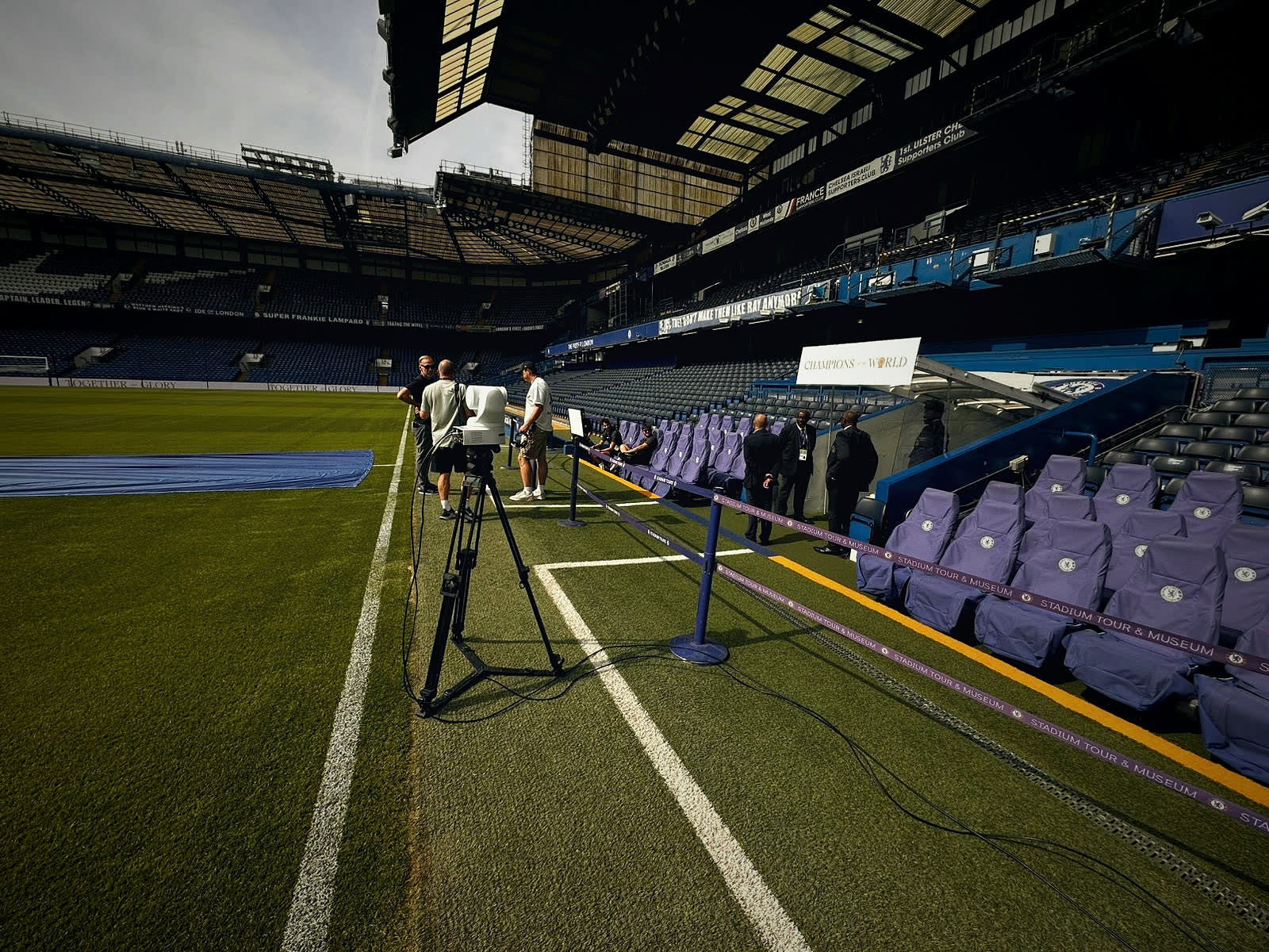 A remote camera on a tripod by the touchline at Stamford Bridge, with our crew beside it.